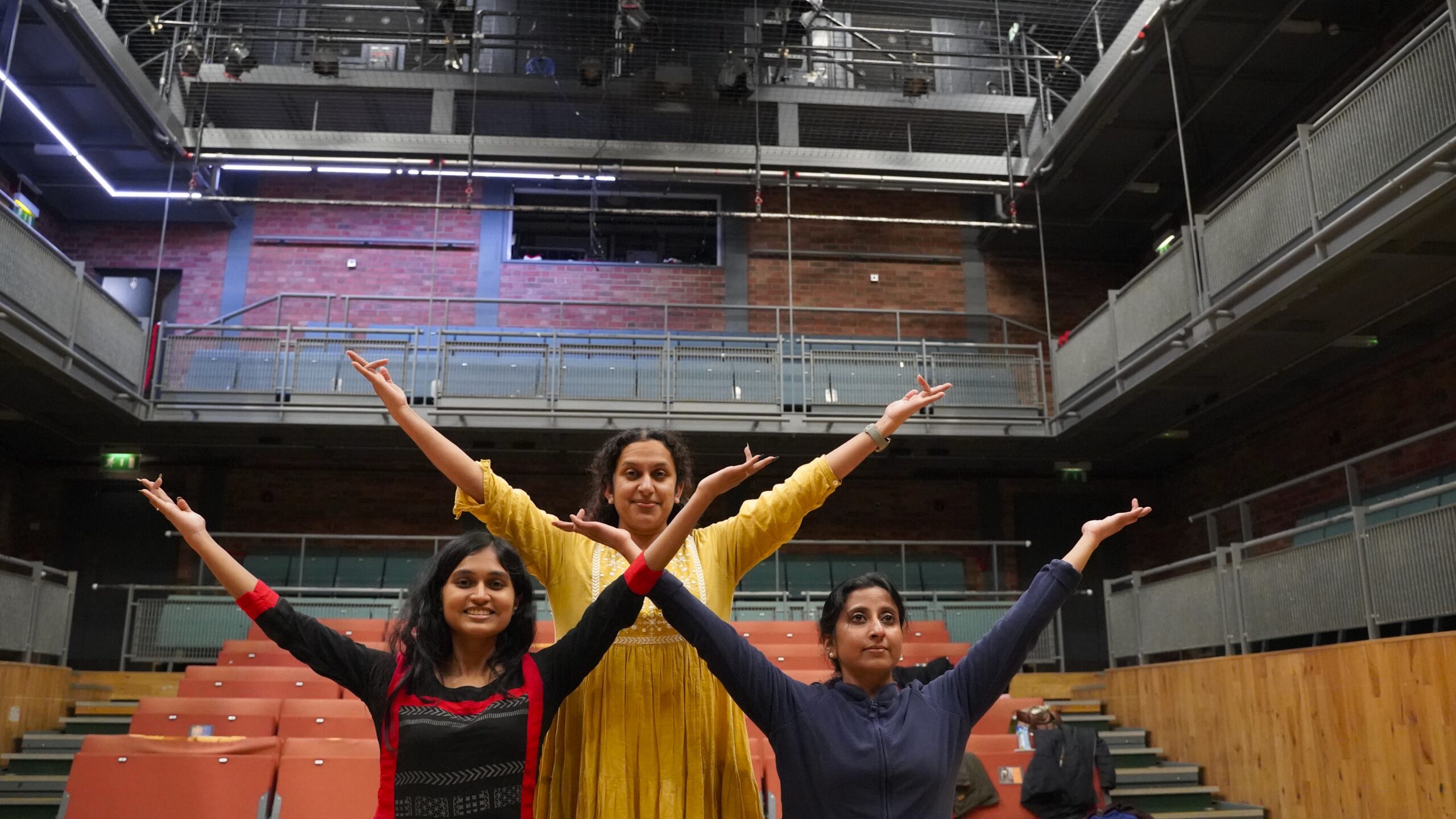 Three dancers with arms raised like trees