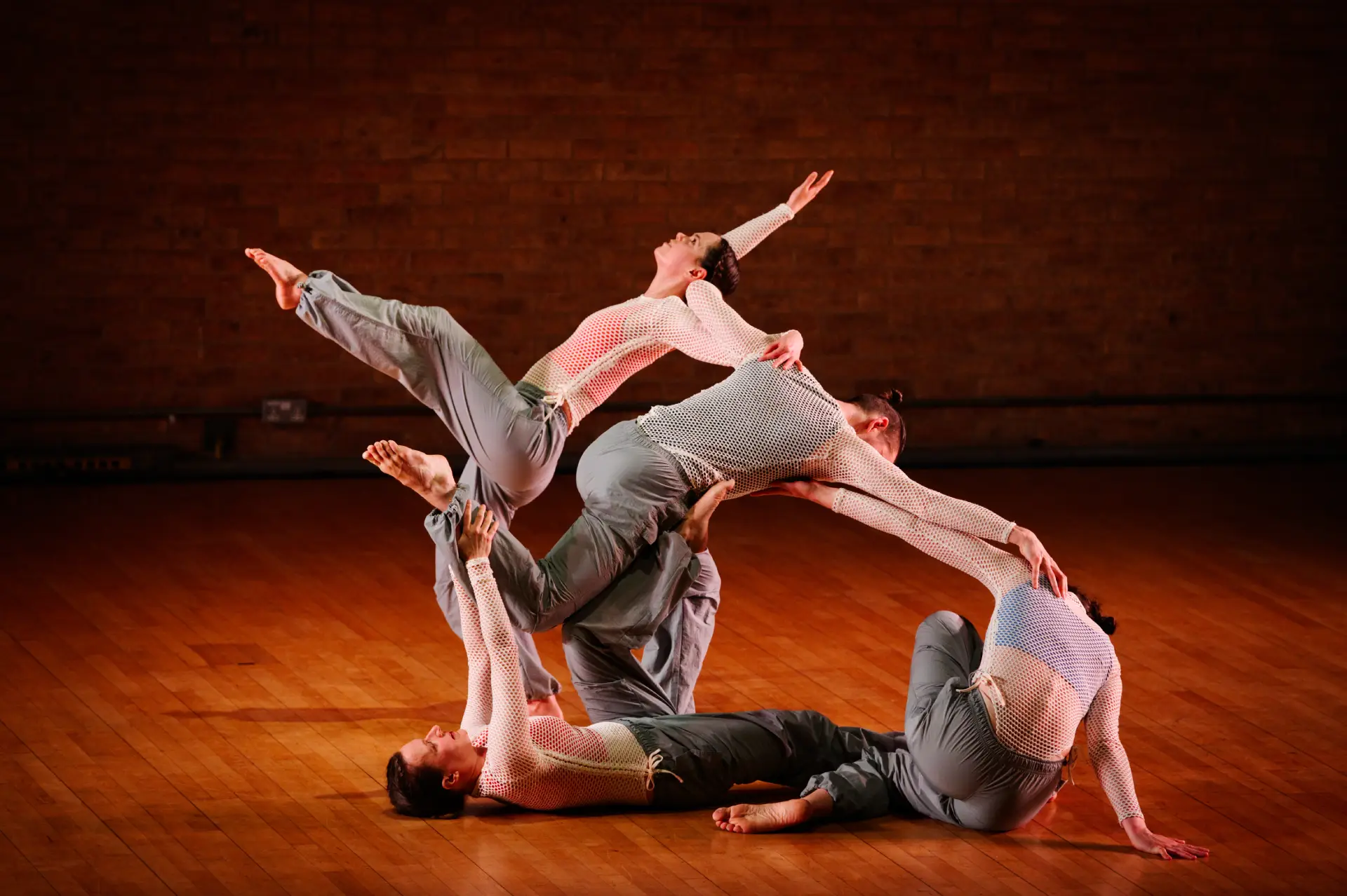 Four dancers in floor and raised poses, interlocking